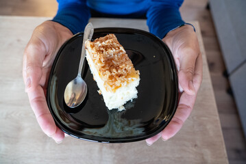 The woman holds food in her hand. the girl holds in her hands. Cake on plate.