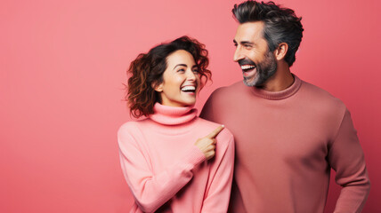 Against a pink background, a young woman and a man smile at each other, symbolizing a happy and close partnership. - obrazy, fototapety, plakaty