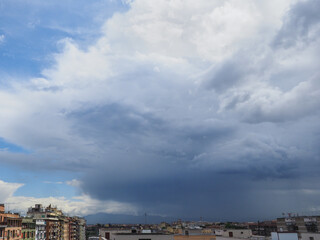 The storm or hurricane is coming. Beautiful dark summer rainy clouds in a blue sky background covered the Rome city in Italy
