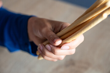 The woman holds food in her hand. Girl holds Grissini in her hands. Italian grissini holding by women.