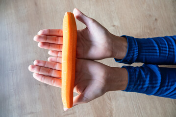 The woman holds food in her hand. the girl holds carrots in her hands. Orange carrot in hand