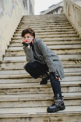 Young girl in coat with short black hair posing on stairs. Lifestyle. Outdoor autumn