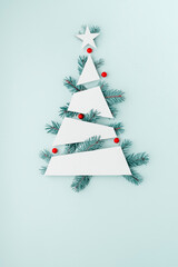 Creative minimalistic Christmas tree mockup with blue Christmas tree branches and red berries on...
