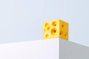 Square yellow piece of cheese stands on the corner of a cube on a blue background.