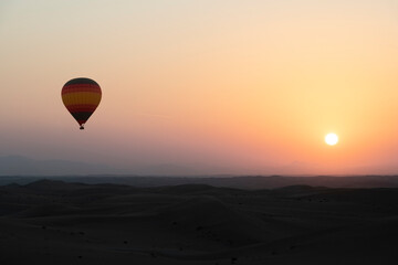 Hot Air Balloon above the desert at sunrise with colourful yellow orange sky and sun. Large copy space for title or other text.