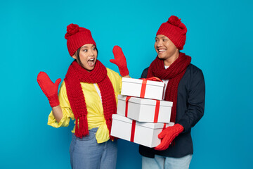 Smiling young asian man in hat gives many boxes present to surprised lady