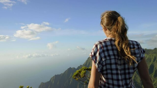Woman running up hill to gorgeous view of Hawaiian valley and mountains