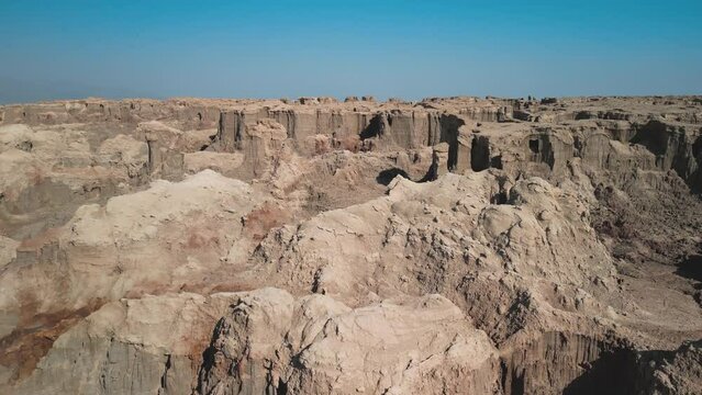 Dallol Desert Salt Canyon, Danakil Depression, Ethiopia.  Aerial view of mountain cliffs and volcanic ravines. Cinematic drone footage going forward, panning down. Famous adventure travel destination.