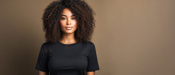 Young dark-skinned woman in black T-shirt smiling and posing at camera, brown background, copy space