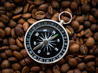 Compass lies on roasted coffee beans. Find your way.