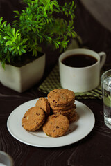 Crunchy cookies biscuits served in plate with black coffee and glass of water isolated on table side view of american cafe baked food