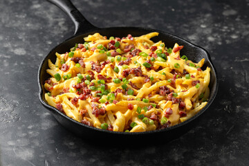 Crispy French fries loaded with bacon, cheese sauce and spring onion in iron cast pan