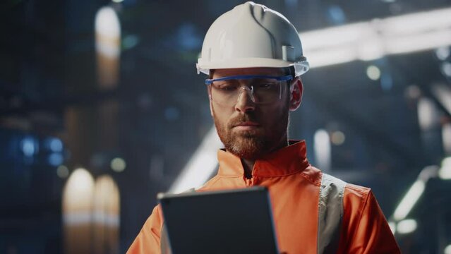 Skilled technician inspecting production industrial facility with tablet closeup
