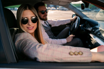 Business couple in the luxury car , closeup shot, both looking at camera 