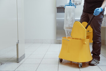 unrecognizable woman using a yellow mop bucket - obrazy, fototapety, plakaty