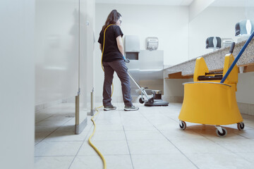 woman scrubbing the bathroom floor with an industrial machine