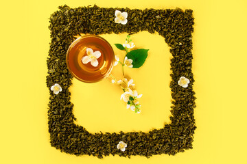 Mockup of dried tea leaves and fresh jasmine flowers shaped in square clock Frame with tea cup in...
