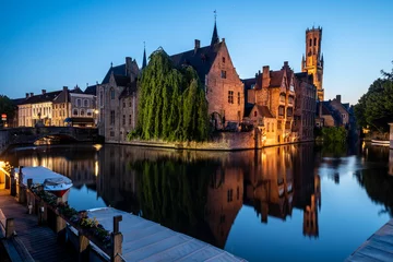 Gordijnen Famous medieval buildings of Brugge with beautiful reflection illuminated during blue hour  © Donald