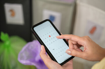 Close up calendar in smartphone holding by hands of Japanese housewife for checking separated...