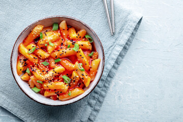 Tteokbokki or topokki, Korean street food, spicy rice cakes in red pepper gochujang sauce, overhead flat lay shot with a place for text