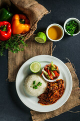 Jamaican Mutton gravy with plain rice, salad, tomato, cucumber dip, sauce and bell pepper served in plate isolated on napkin top view of lunch food