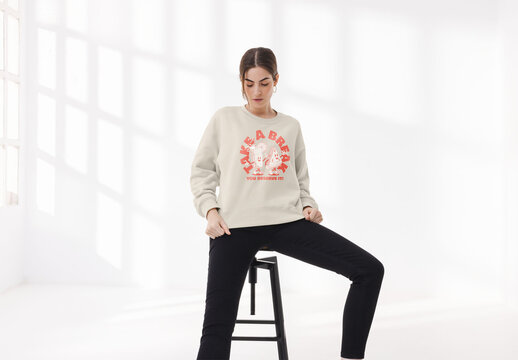 Mockup of young woman wearing customizable sweatshirt, on stool
