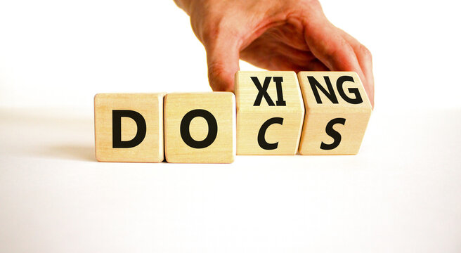 Docs or doxing symbol. Concept words Docs Doxing on wooden block. Beautiful white table white background. Businessman hand. Business docs or doxing concept. Copy space.