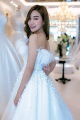 Naklejka premium Bride and groom wear dress and try to fitting in modern wedding studio with bridal store owner