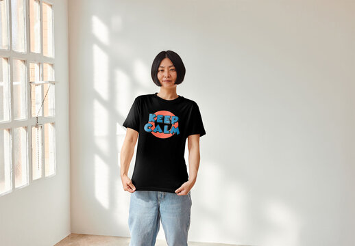 Mockup of young Asian woman by window wearing customizable t-shirt