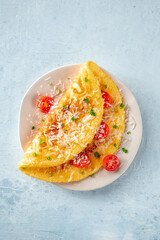 An omelet with tomato and parsley, eggs for breakfast, a healthy vegetarian dish with cheese, top shot