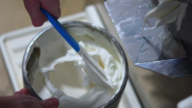 ice cream coming out of batch freezer machine into the container, closeup shot. High quality 4k footage