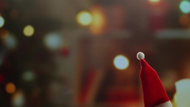 Little Christmas hat on background close-up. Elf, dwarf in red hat walking at home near christmas tree. Vibes of winter holidays,2024, 2025