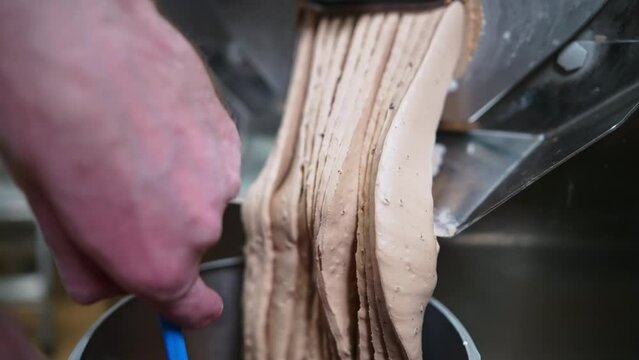 Chocolate ice cream coming out of batch freezer machine into the container, closeup shot. High quality 4k footage