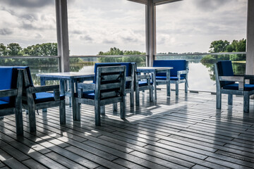 Interior of a summer cafe. Vintage homemade chairs and tables. Lake view.