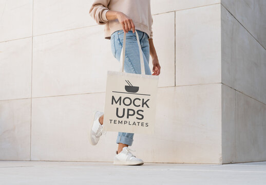 Mockup of woman holding customizable tote bag, low section