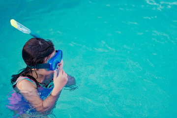 Girl in snorkel gear diving in a turquoise pool.