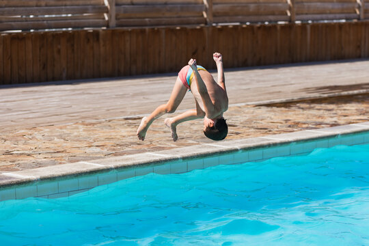 Youth boy diving headfirst into clear blue pool.