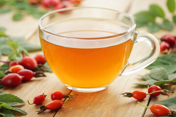 Rosehip tea with fresh red dog-rose berries on wooden table, closeup, copy space, vitamin...