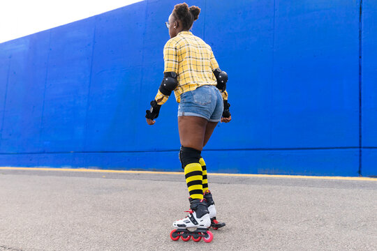 Woman Rollerskating On Rink At Skate Park Along Blue Wall