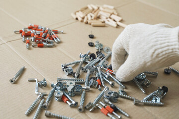 A male worker goes through the furniture fasteners after unpacking, preparing to assemble the furniture.