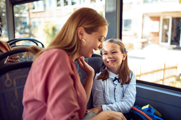 Young girl smiling at her mother while traveling on a bus