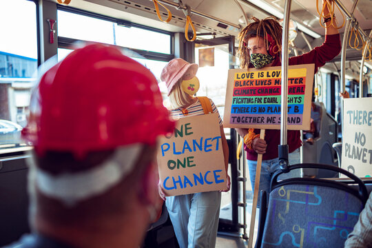 Activists Holding Signs About Social And Environmental Issues On A Bus