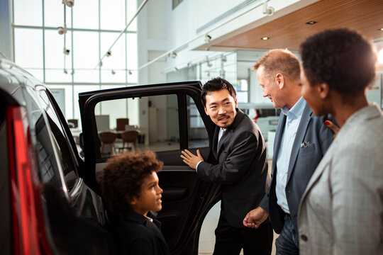 Salesman explaining car features to a family at the dealership
