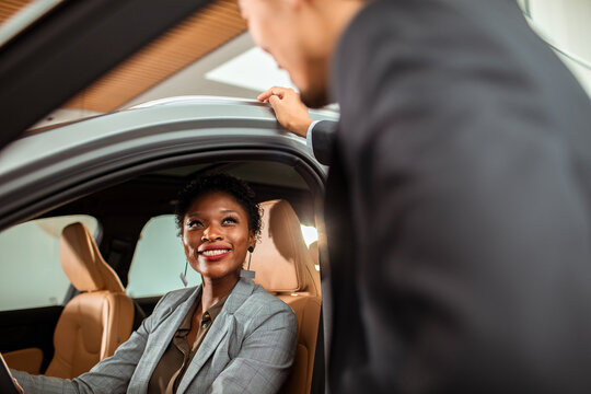 Sales representative discussing car features with a potential buyer at a dealership