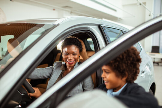 Joyful mother and son exploring a new car at a dealership