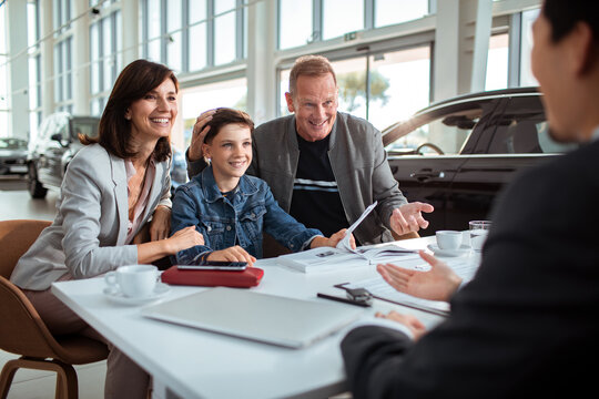Family discussing with a salesperson at a car dealership