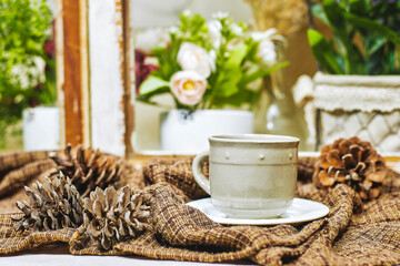 winter concept, cozy scarf with cup of coffee with cone pine near window 