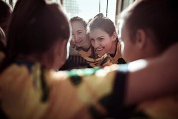 Female soccer players huddle together in unity in the locker room