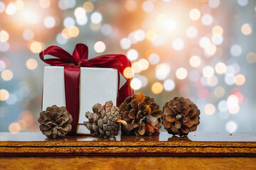 christmas and new year background - gift boxes and pine cones on wood table with  background of bokeh garlands