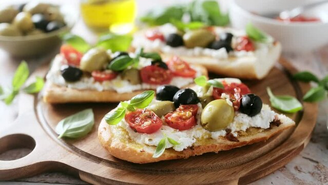 Sandwiches with bruschetta or toasts, cream cheese, baked tomatoes and marinated olives. Antipasti bruschetta, Mediterranean food appetizer. Stock video 4k